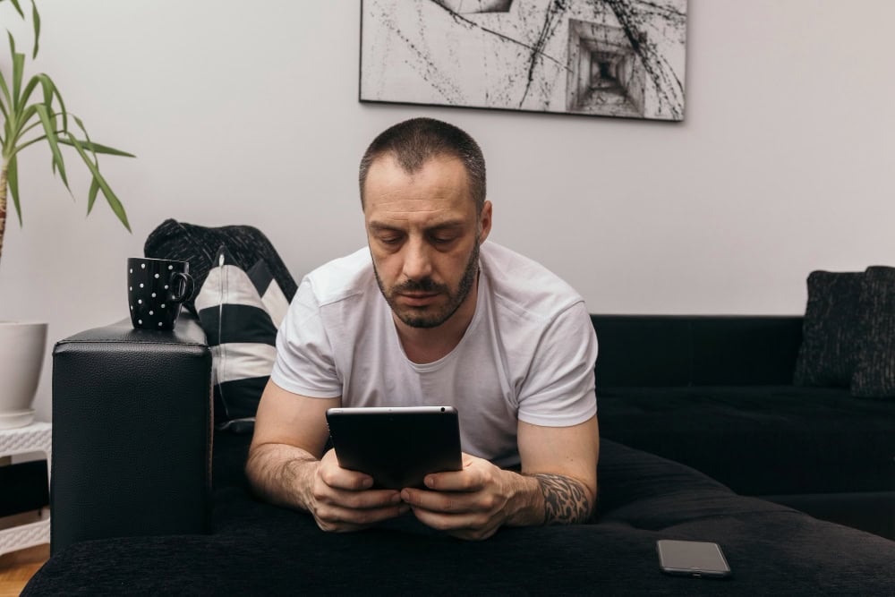 Man using tablet while participating in online addiction treatment in Washington at home
