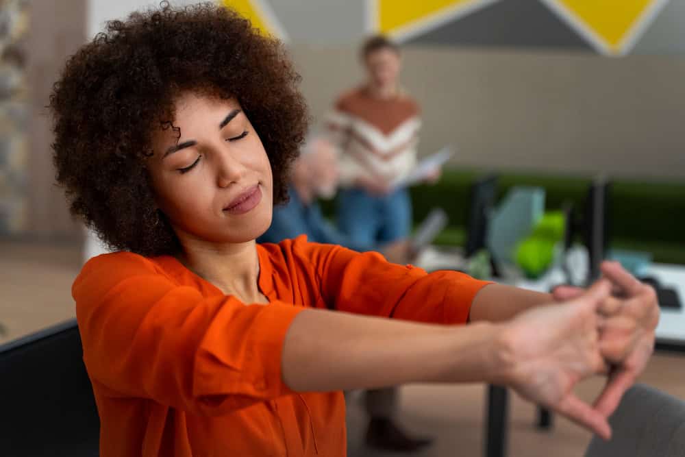 Woman stretching at office during workday while using online mental health treatment in Washington support