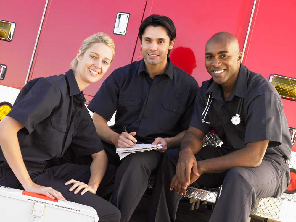 Three paramedics completing paperwork beside their ambulance while accessing behavioral health support for first responders in Washington State.