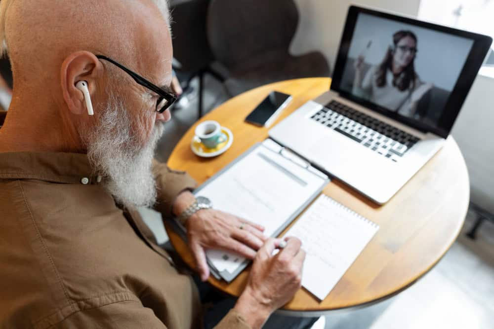 Senior man taking notes during Virtual CBT in Washington therapy session