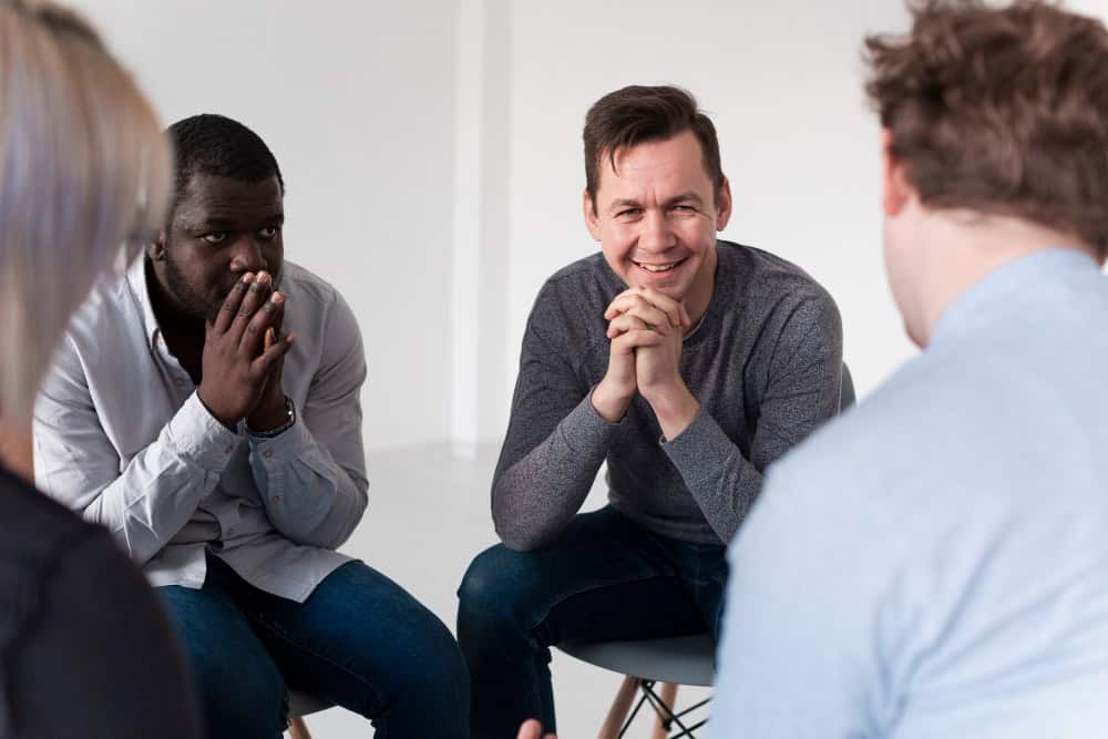 Man smiling while talking with friends during an intensive outpatient program in Washington State at Clarity Healthcare.